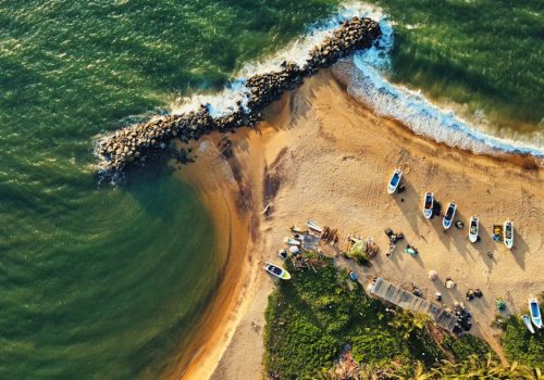 Stunning drone shot of Katuneriya Beach featuring boats, crashing waves, and tetrapods.