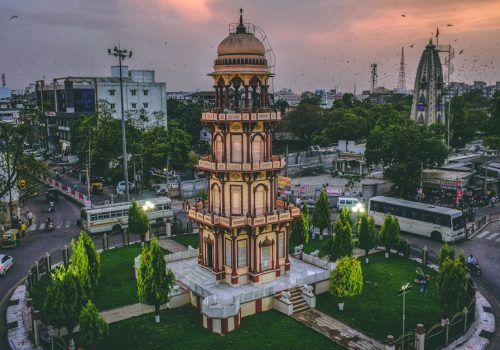 Aerial view of a historic tower in Ahmedabad, India at dusk surrounded by urban cityscape.