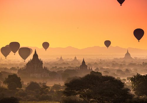 Captivating view of hot air balloons floating over ancient temples in Bagan, Myanmar at sunrise.