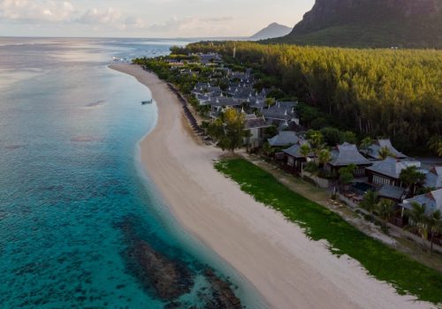 Aerial photograph of a tranquil beach resort in Mauritius with clear waters and lush greenery.