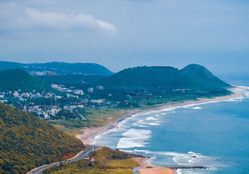 A breathtaking aerial view of the coastline in Visakhapatnam, capturing lush hills and the vibrant sea.